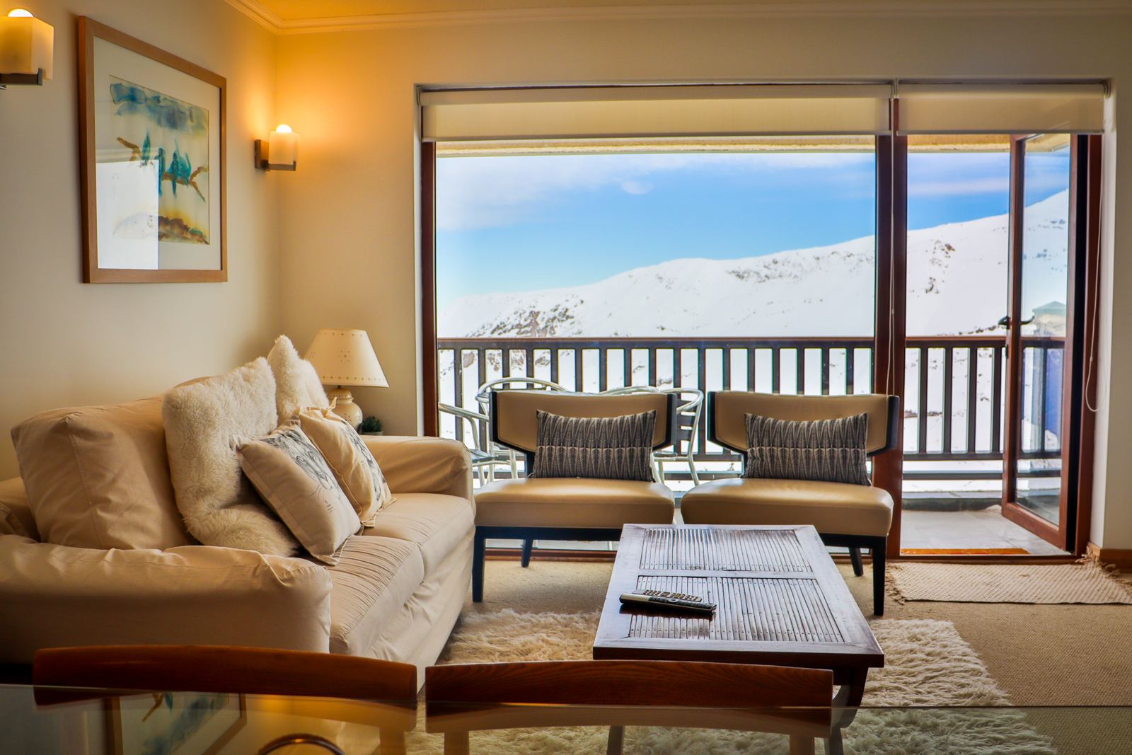 Living con sofás claros y salida a terraza con vista a las canchas de Valle Nevado