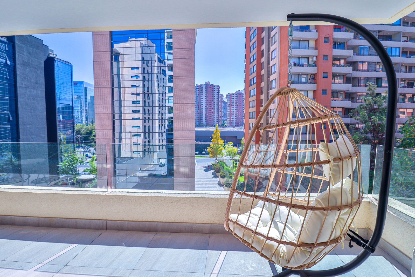 Terraza con silla colgante y vista a las torres del sector financiero de Santiago