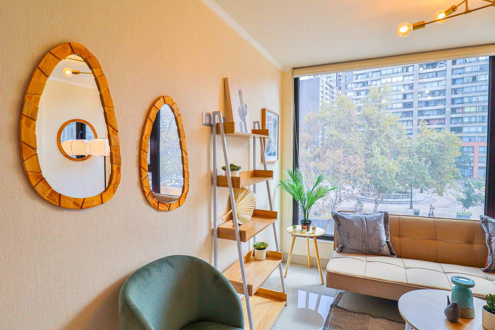 Living con espejos de madera, repisa escalera y ventanal hacia la plaza